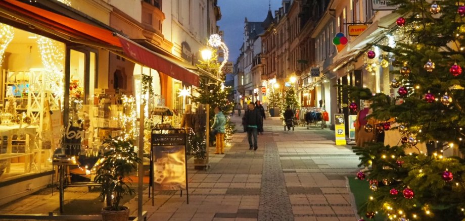 Beleuchtete Fußgängerzone mit Tannenbäumen und Lichtern zur Weihnachtszeit