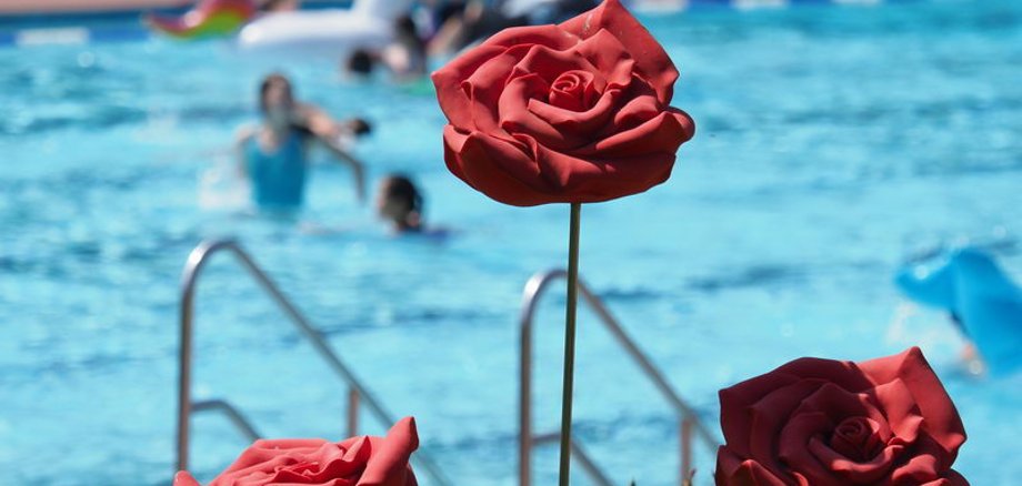 Drei rote Rosen aus Metall, im Hintergrund ist das Becken zu sehen.