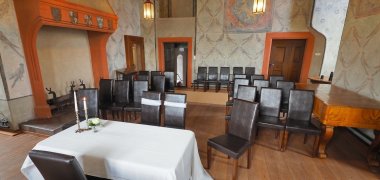 Bestuhlter Raum mit Wandmalerei, orangenen Verzierungen und einem Ofen.