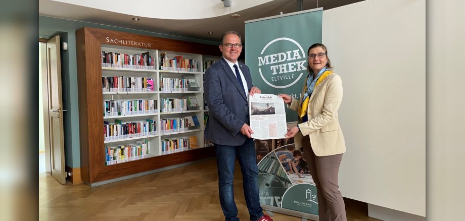 Bürgermeister Kunkel und Barbara Lilje halten das Extrablatt in der Mediathek in den Händen