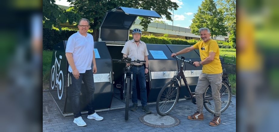 Bürgermeister, Stadtrat und Mitarbeiter der Stadt mit Rädern vor den neuen Radboxen