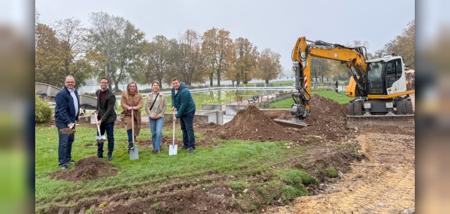 Gruppenfoto mit symbolischen Spatenstich und Bagger im Hintergrund