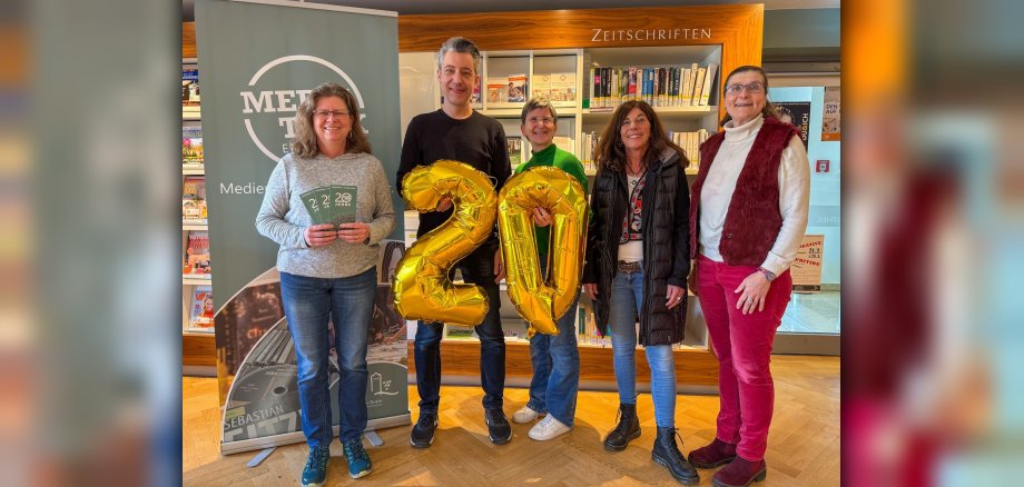 Gruppenfoto mit goldenen Luftballons der Zahl 20 in den Händen